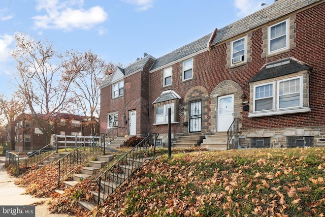 townhome / multi-family property with entry steps, a high end roof, brick siding, and a residential view