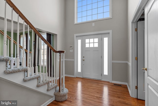 entrance foyer with a high ceiling, wood finished floors, visible vents, and baseboards