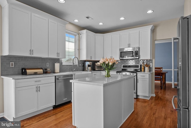 kitchen featuring visible vents, wood finished floors, appliances with stainless steel finishes, and white cabinets