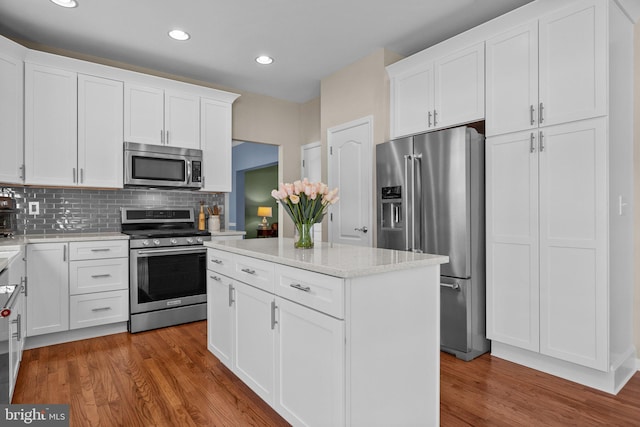 kitchen with backsplash, appliances with stainless steel finishes, wood finished floors, and white cabinets