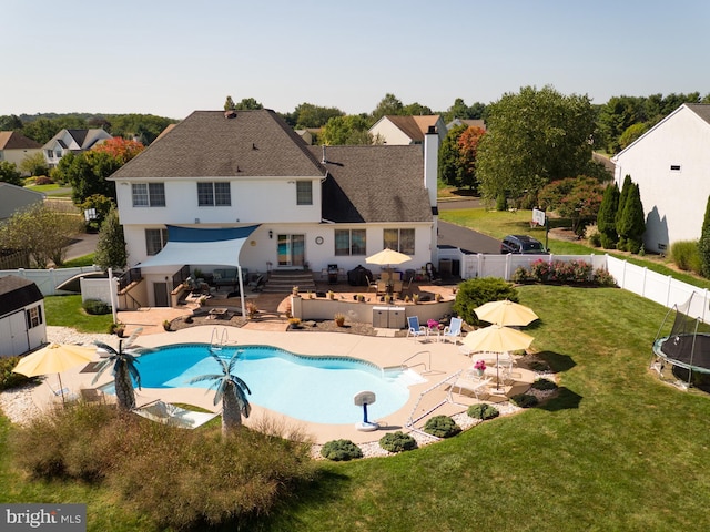 view of swimming pool featuring a patio area, a lawn, a fenced backyard, and a trampoline