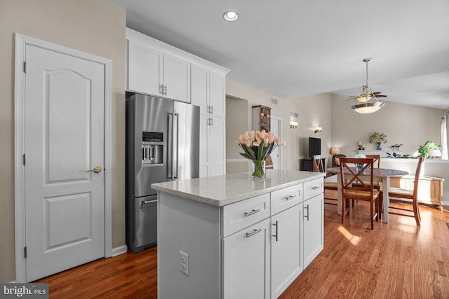 kitchen featuring pendant lighting, high end fridge, a kitchen island, wood finished floors, and white cabinetry