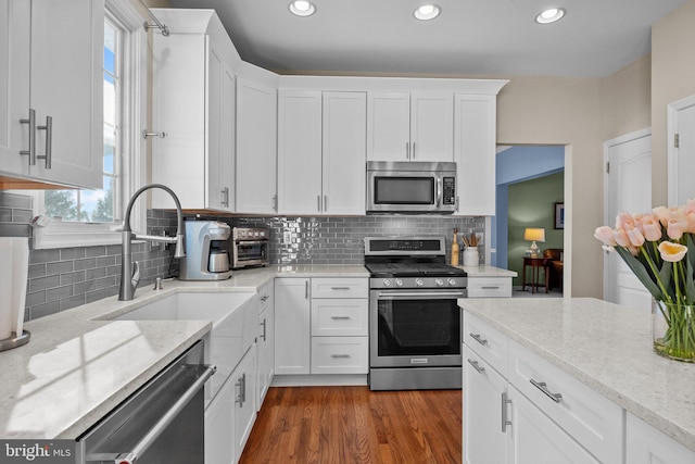 kitchen with white cabinetry, wood finished floors, appliances with stainless steel finishes, and a sink