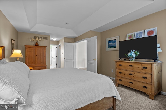 bedroom with a tray ceiling, light colored carpet, and baseboards