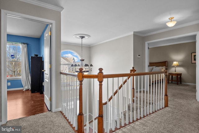 hall with an upstairs landing, carpet flooring, and ornamental molding