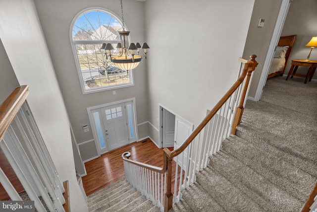 foyer with baseboards, a high ceiling, an inviting chandelier, and wood finished floors