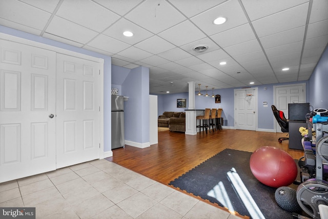 exercise room featuring wood finished floors, visible vents, a drop ceiling, and baseboards