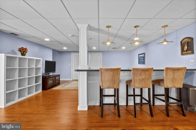 kitchen with visible vents, pendant lighting, a breakfast bar, dark countertops, and wood finished floors