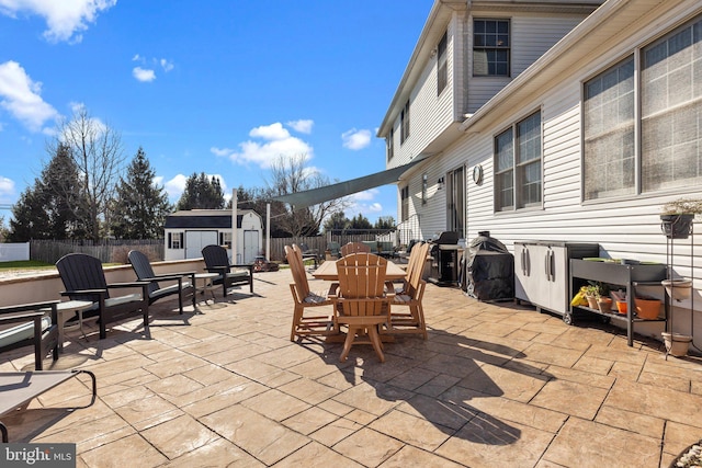 view of patio featuring outdoor dining space, a storage shed, an outbuilding, and a fenced backyard