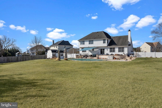 back of house with a lawn, a patio, a chimney, and a fenced backyard