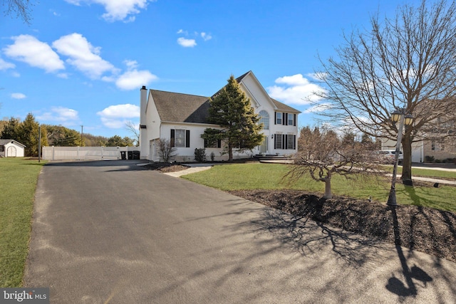 view of front of home featuring a front yard, a chimney, driveway, and fence