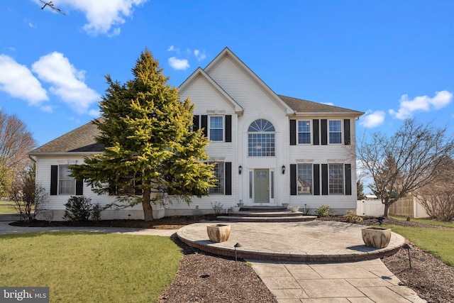 view of front facade with a front lawn, fence, and a shingled roof