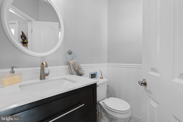 bathroom with vanity, toilet, and wainscoting