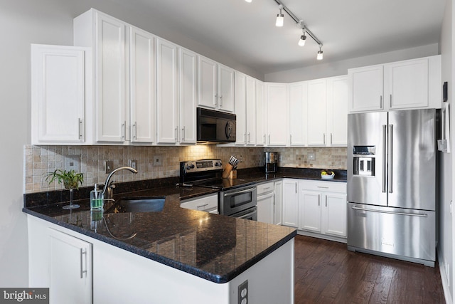 kitchen with dark wood finished floors, a peninsula, a sink, decorative backsplash, and stainless steel appliances