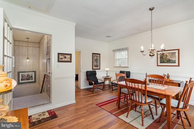 dining room with crown molding, a notable chandelier, wood finished floors, and visible vents