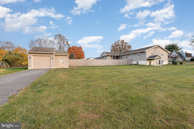 view of yard with driveway, an attached garage, and fence