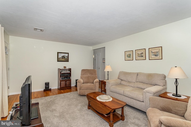 living room with visible vents, baseboards, and wood finished floors