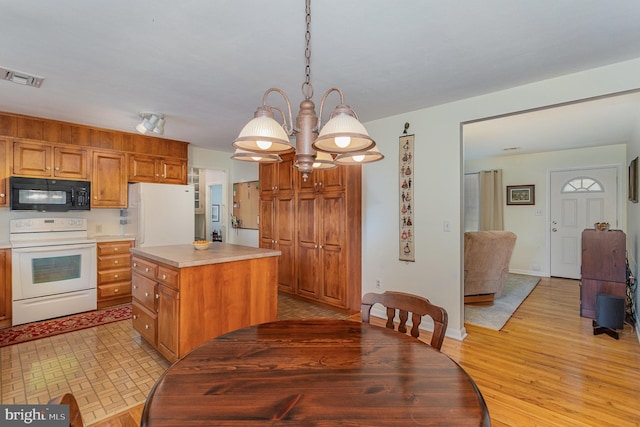 kitchen featuring visible vents, a kitchen island, white appliances, light wood-style floors, and light countertops