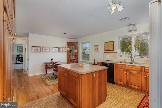 kitchen with visible vents, a sink, a kitchen island, light countertops, and dishwasher