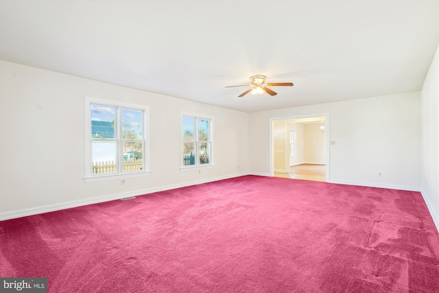 carpeted empty room with visible vents, a ceiling fan, and baseboards