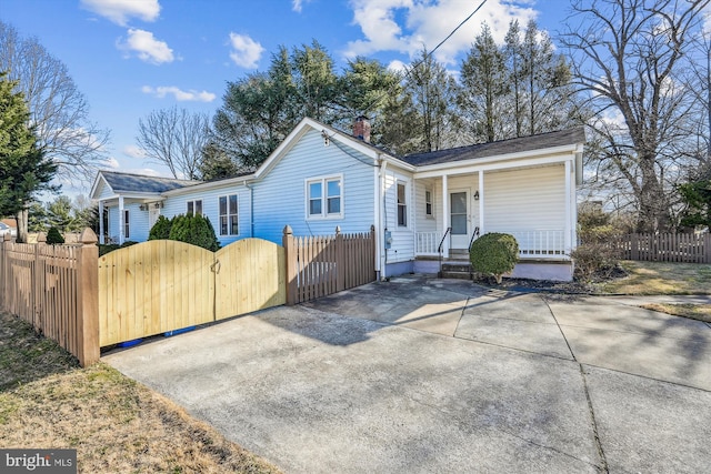 view of front of home with a gate, covered porch, a fenced front yard, and a chimney