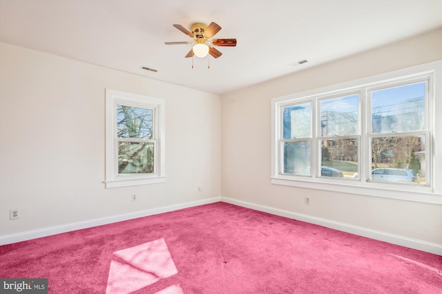 carpeted empty room with visible vents, baseboards, and a ceiling fan