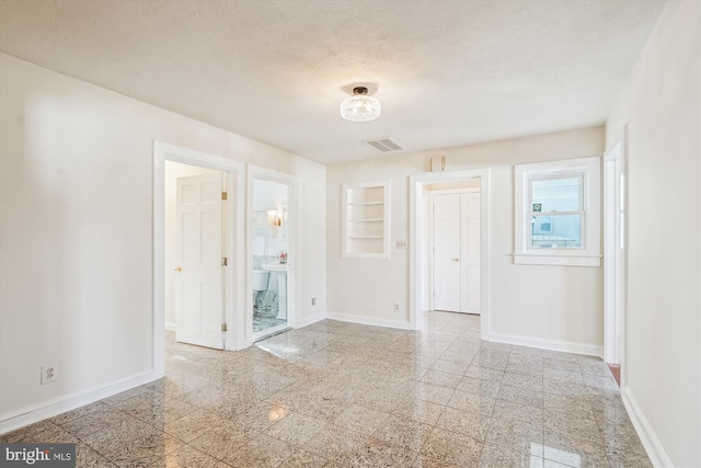 empty room with visible vents, baseboards, a textured ceiling, and granite finish floor