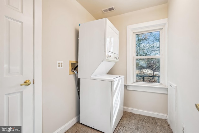 clothes washing area with visible vents, baseboards, stacked washer and dryer, and laundry area