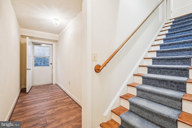 staircase with baseboards and wood finished floors