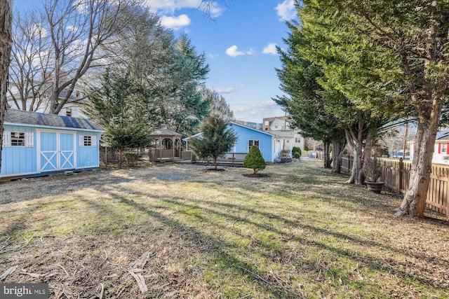 view of yard featuring an outbuilding, fence, and a shed