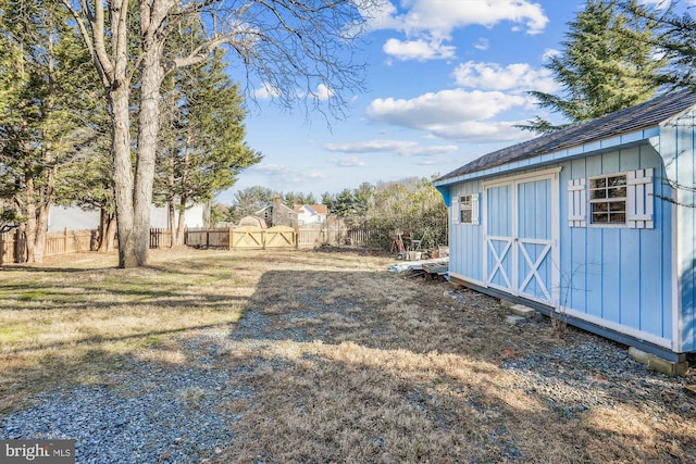 view of yard featuring an outbuilding, a storage unit, a gate, and fence