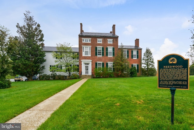 view of front of house with a front yard, brick siding, and a chimney