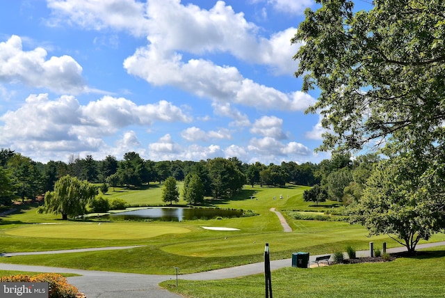 surrounding community with golf course view, a water view, and a yard