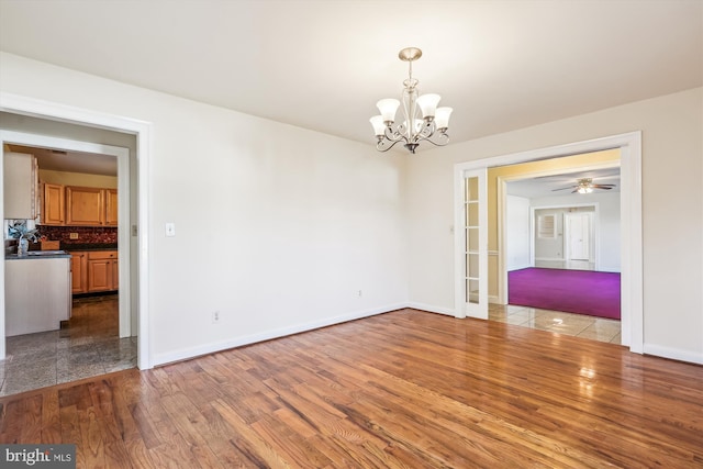 empty room featuring a notable chandelier, wood finished floors, and baseboards