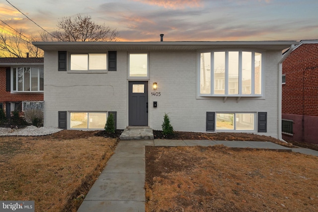 view of front of home featuring brick siding and a lawn