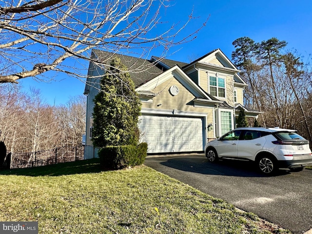 view of property exterior featuring aphalt driveway, an attached garage, a yard, and fence