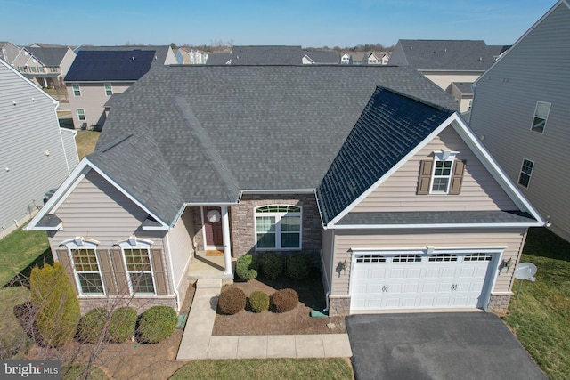 view of front of home with a garage, stone siding, driveway, and roof with shingles