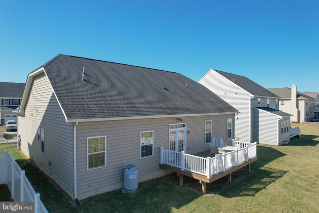 rear view of property with a wooden deck, a yard, roof with shingles, and fence