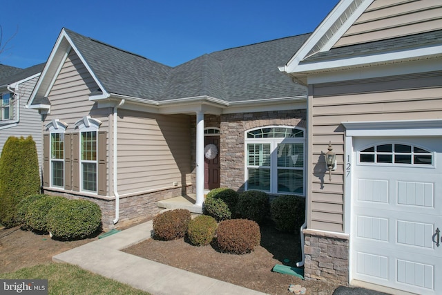 property entrance featuring french doors, stone siding, a garage, and a shingled roof