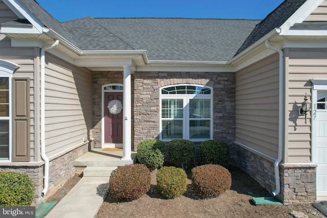 property entrance featuring stone siding and a shingled roof