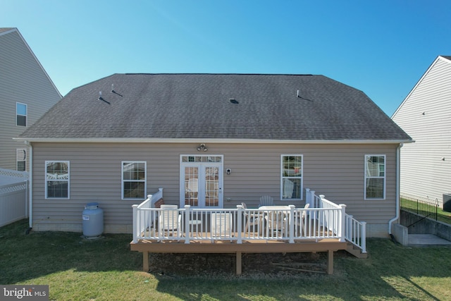 rear view of house featuring a lawn, a shingled roof, a deck, and fence