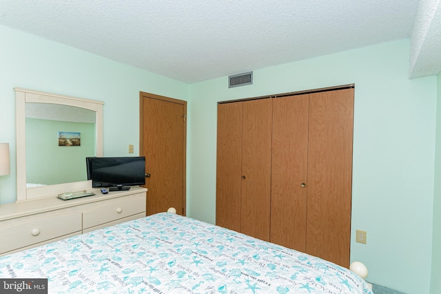 bedroom with visible vents, a textured ceiling, and a closet