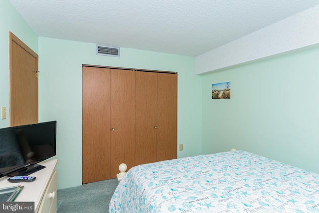 bedroom with a closet, a textured ceiling, visible vents, and carpet flooring