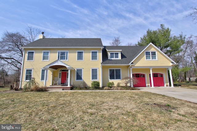 colonial inspired home featuring a chimney, a front lawn, concrete driveway, and a garage