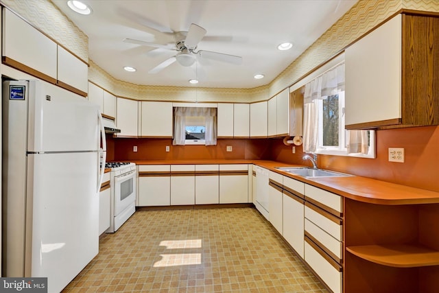 kitchen with a sink, white appliances, light countertops, and white cabinetry