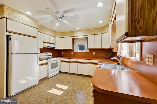 kitchen featuring under cabinet range hood, white cabinets, white appliances, a ceiling fan, and a sink