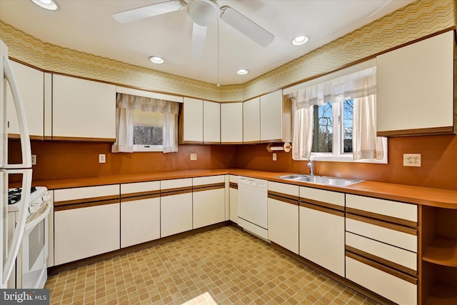 kitchen with white appliances, white cabinetry, light countertops, and a sink