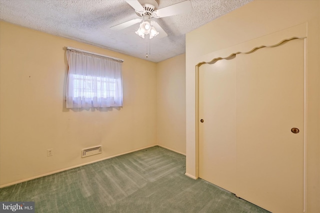 spare room featuring ceiling fan, carpet, visible vents, and a textured ceiling