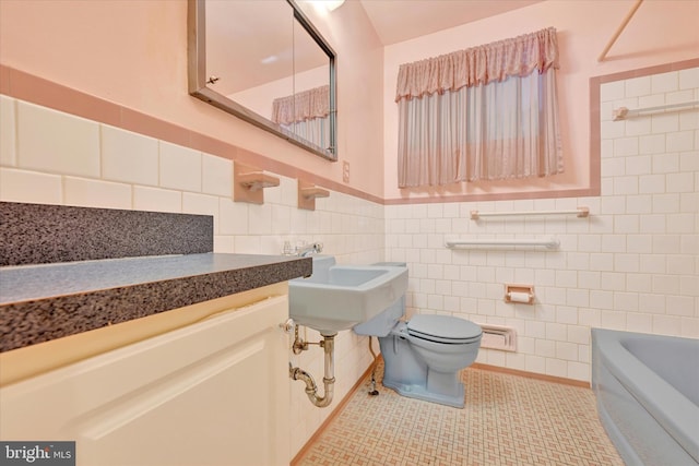 bathroom featuring toilet, a tub to relax in, a sink, tile walls, and tile patterned flooring