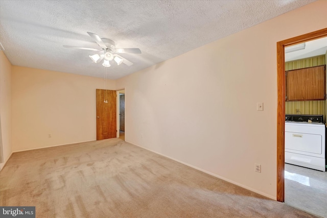 spare room with a ceiling fan, a textured ceiling, carpet flooring, baseboards, and washer / dryer